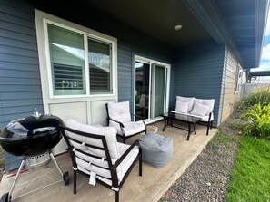 Eine Terrasse mit Gartenmöbeln, einem Grill und einer Schiebetür.