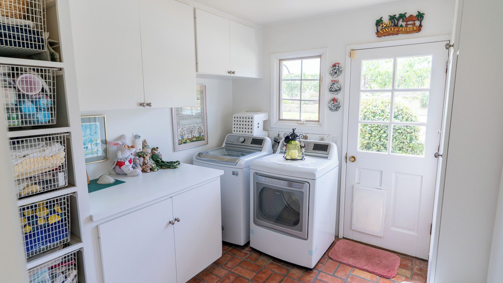 A laundry room with two washing machines, a dryer, and a white door with a window.