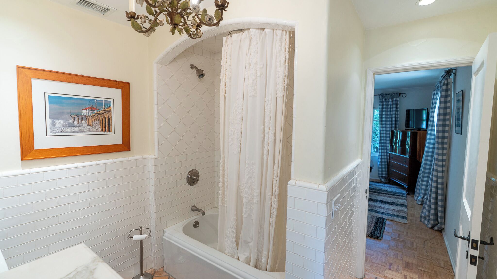 A bathroom with a bathtub, shower curtain, and a framed picture on the wall.