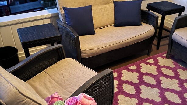 En mysig utomhusplats med en soffa, stolar och ett litet bord.