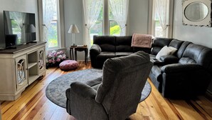 Ett vardagsrum med en soffa, en fåtölj, en tv och en takfläkt.