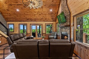 Un interior de madera con chimenea, sofá de cuero y ventanas amplias.