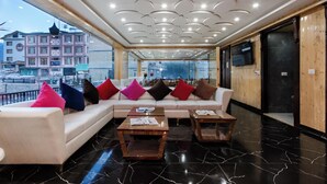 Un vestíbulo moderno con un sofá modular, mesas de madera y un amplio ventanal con vistas a la ciudad.