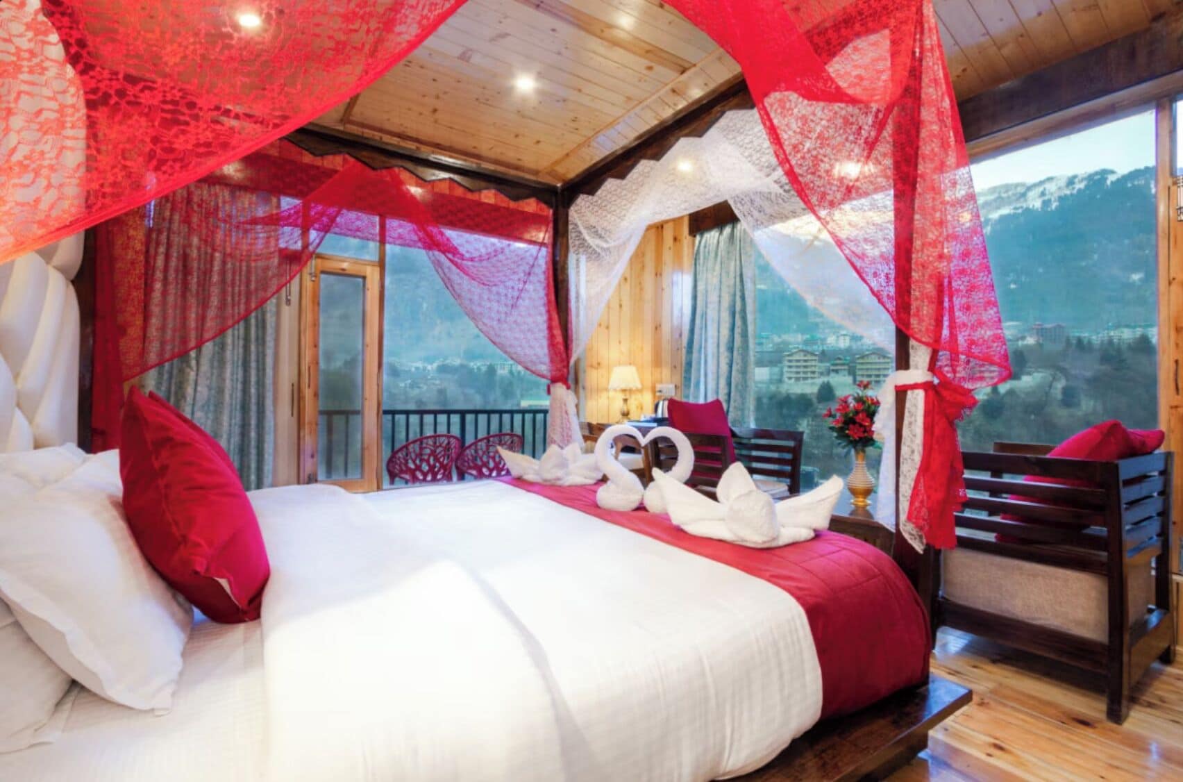 A bedroom with a bed, pillows, a nightstand, a chair, and a window with a view of mountains.