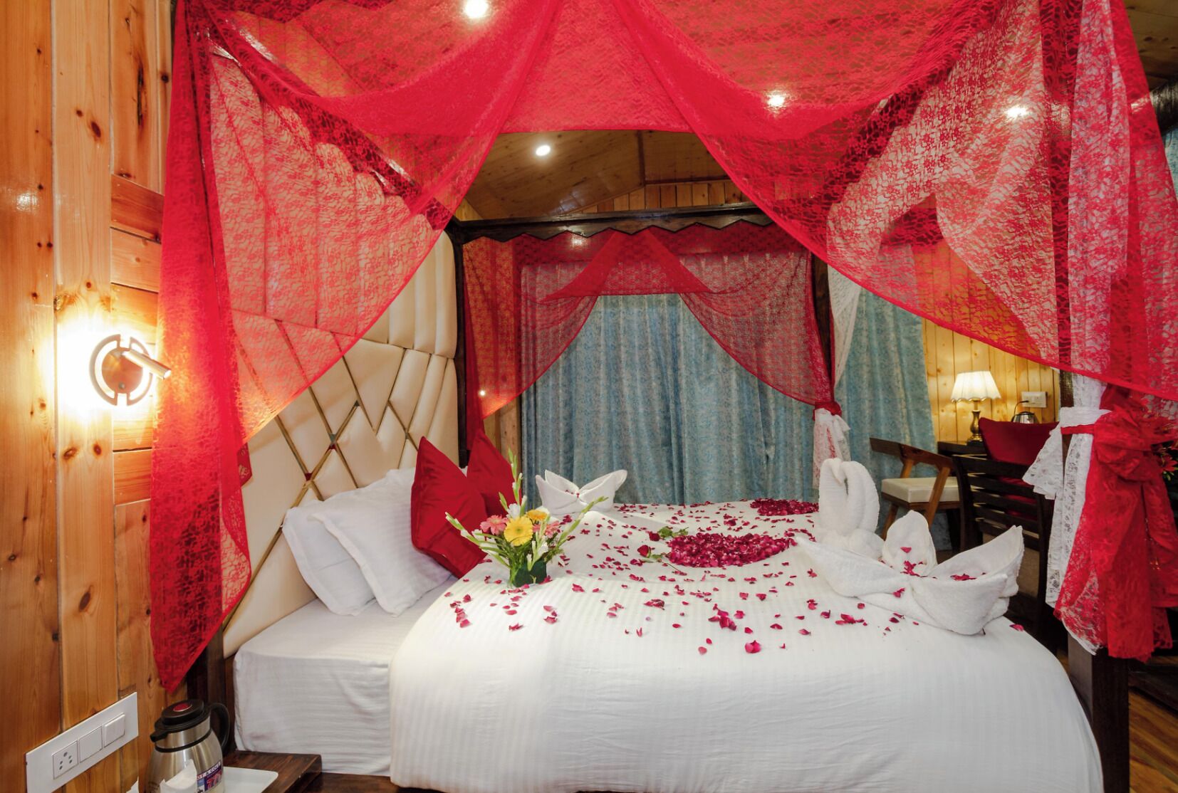 A bed with white linens, red pillows, and a bouquet of flowers.