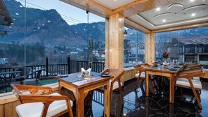 Un restaurante con vistas a la montaña, interior de madera y suelo de mármol negro.