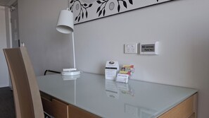 A clean, modern room with a desk, a white lamp, a 'NO SMOKING' sign, and a wall-mounted charging station. - 1-bedroom apartment, Darwin city with sunset and harbour views for family of 4 (Darwin City)