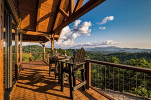 A wooden deck with a table and chairs, overlooking a mountainous landscape. - Private Wellness Retreat | Epic Mtn Views + Sauna (Sevierville)