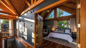 Un'ampia camera da letto con un letto grande, pavimento in legno e un balcone.