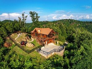 A large wooden house with a balcony, surrounded by lush greenery and a clear sky. - Private Wellness Retreat | Epic Mtn Views + Sauna (Sevierville)