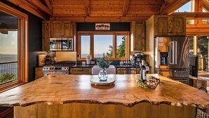 Una cucina con una grande isola, elettrodomestici in acciaio inossidabile, mobili in legno e vista sull'esterno.