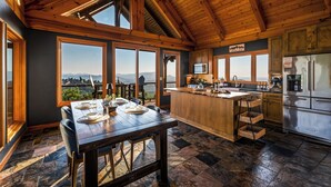 Cucina spaziosa con un'isola grande, soffitto in legno e ampie finestre che offrono vista sulle montagne.