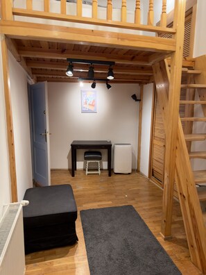 Ein Zimmer mit Schlafkoje, Schreibtisch, Heizkörper und Treppe.