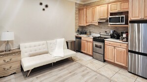 Une cuisine moderne avec des meubles en bois, des appareils électroménagers en acier inoxydable et un canapé beige.