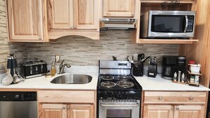 Une cuisine avec des meubles en bois, une cuisinière en acier inoxydable, un four à micro-ondes et un lave-vaisselle.