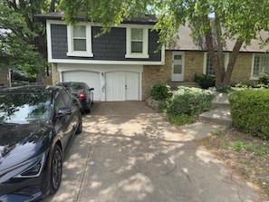 Ein zweistöckiges Haus mit Garage, Auffahrt und Baum davor.