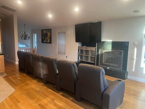 Ein modernes Wohnzimmer mit einer langen Couch, einem Flachbildfernseher und einem Kamin.