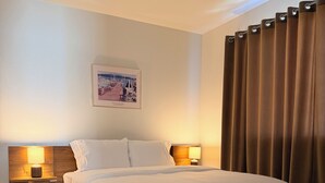 A neatly made bed with white linens, a wooden headboard, and two bedside lamps. - Lynnwood Retreat: Office, Theater & Grapevine Deck (Lynnwood)