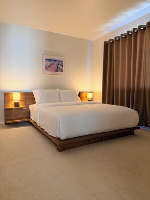 A neatly made bed with white linens, a wooden headboard, and two bedside lamps. - Lynnwood Retreat: Office, Theater & Grapevine Deck (Lynnwood)