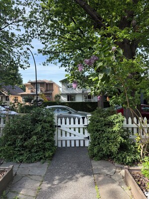 Ein Wohnweg mit weißem Zaun, ein Pfad zum Haus und ein geparktes Auto in der Nähe.