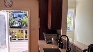 Uma cozinha com armários de madeira, pia de aço inoxidável, torradeira e janela.