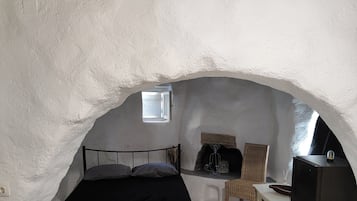 A cozy bedroom with a bed, a small table, a chair, and a television.