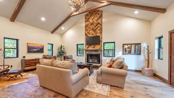 Un salón amplio con chimenea, sofás y un televisor grande.