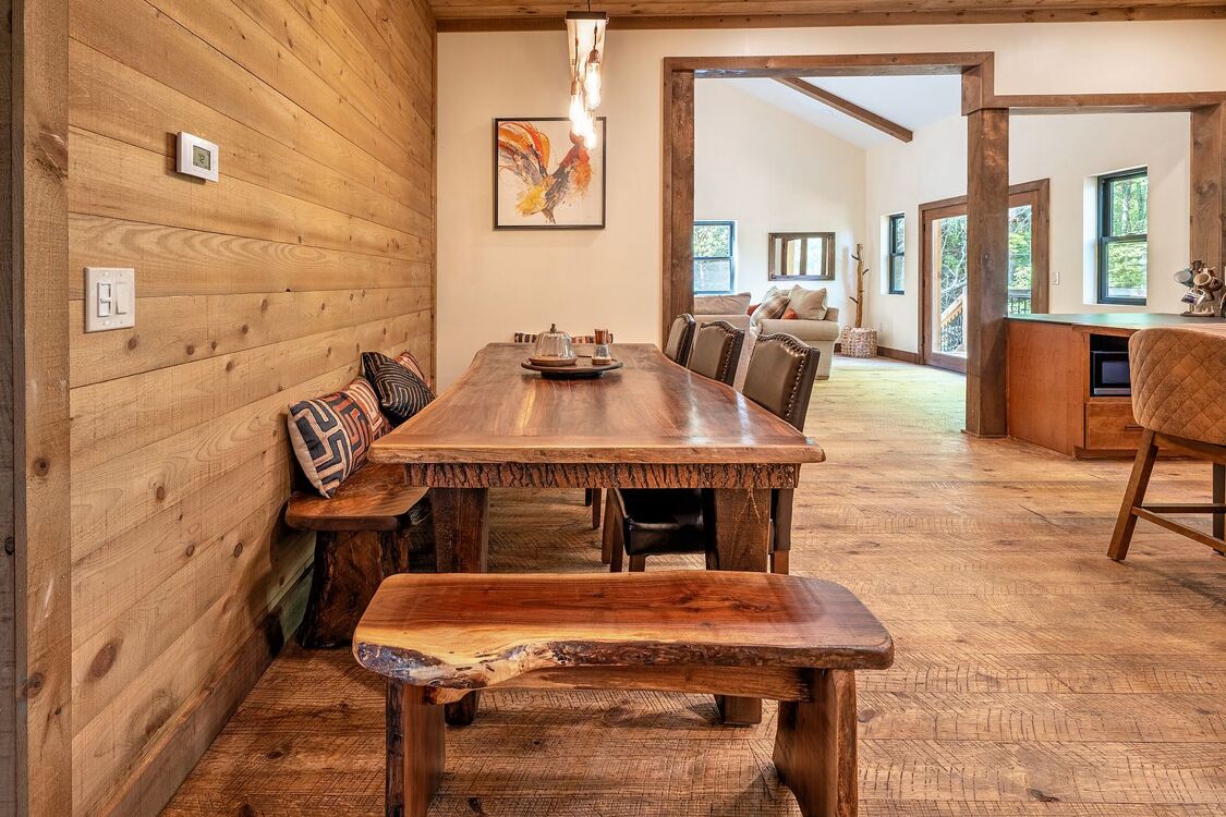 Un interior de madera con una mesa de comedor, bancos y una zona de cocina.
