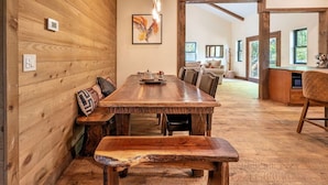 Un interior de madera con una mesa de comedor, bancos y una zona de cocina.