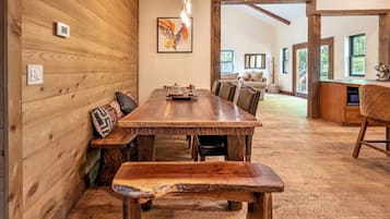 Un interior de madera con una mesa de comedor, bancos y una zona de cocina.