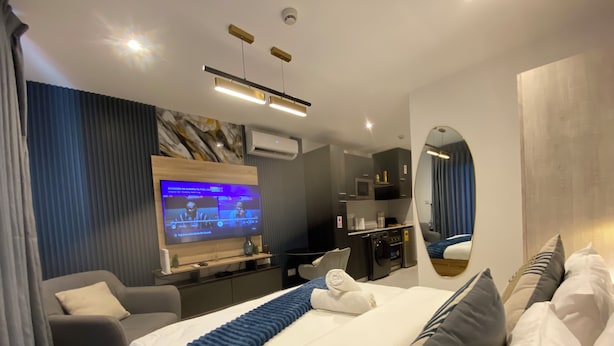Una habitación de hotel moderna con una cama grande, televisión, escritorio y espejo.