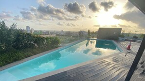 Una piscina en la azotea con vistas despejadas al horizonte de la ciudad y la vegetación circundante.