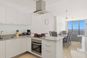 Een moderne keuken met een centraal eiland, roestvrijstalen apparatuur en een eethoek met uitzicht.