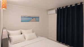 Ein Zimmer mit einem Bett, einem Bild eines Piers, einer Klimaanlage und einem Vorhang.
