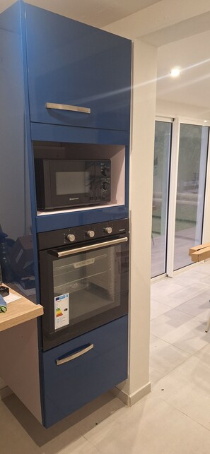 Eine Küche mit eingebautem Backofen, Mikrowelle und einer Holz Arbeitsplatte.
