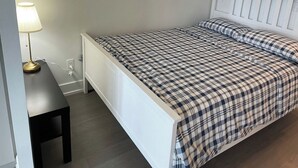 Ett sovrum med en säng, ett nattduksbord och en lampa.
