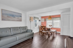 A modern living room with a gray sofa, wooden dining table, and chairs. - Professionally Managed with Outdoor Dining & Coffee (Seaside Heights)