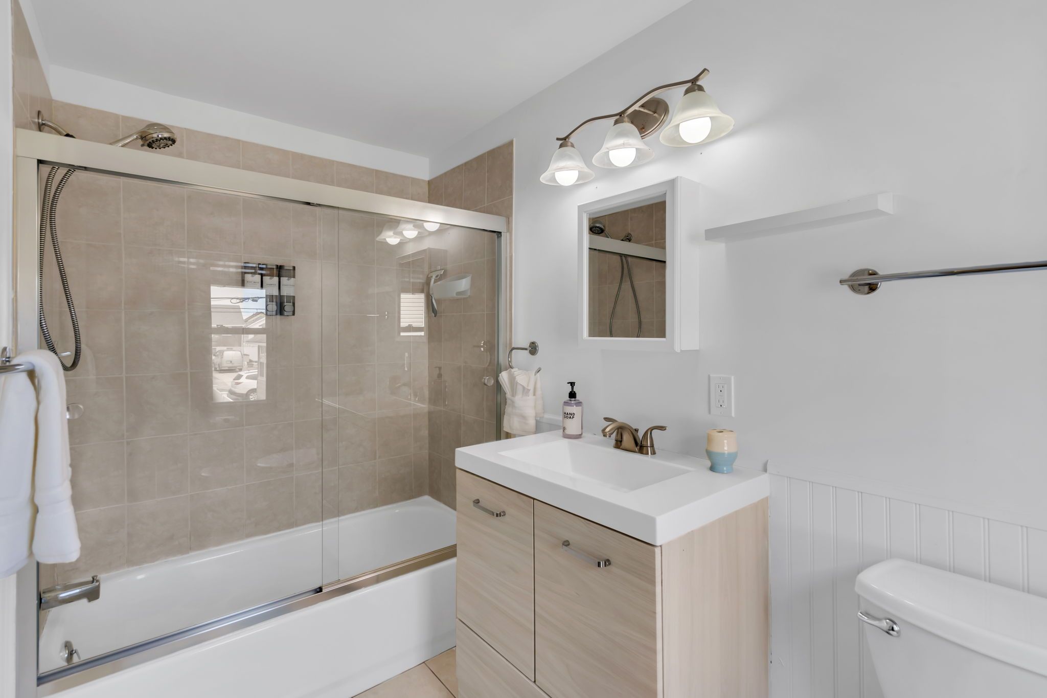 Une salle de bain moderne avec une douche à parois de verre, un lavabo blanc avec un meuble-vasque et des toilettes.