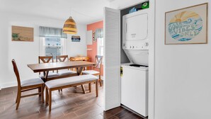 A modern kitchen with a built-in washer and dryer, wooden dining table, and a hanging pendant light. - Professionally Managed | 3 Blocks 2 Beach (Seaside Heights)