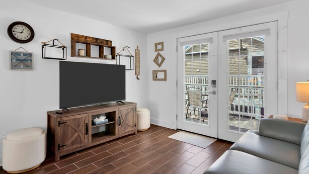 A living room with a TV, wooden cabinet, white walls, and a sliding glass door to the outside. - Professionally Managed | 3 Blocks 2 Beach (Seaside Heights)