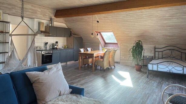 Une pièce de style loft comprenant un coin repas, une cuisine et un lit.