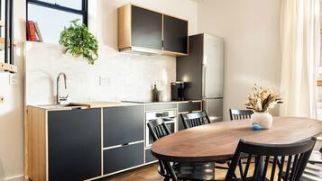 A modern kitchen with a wooden dining table, black chairs, and a built-in oven.