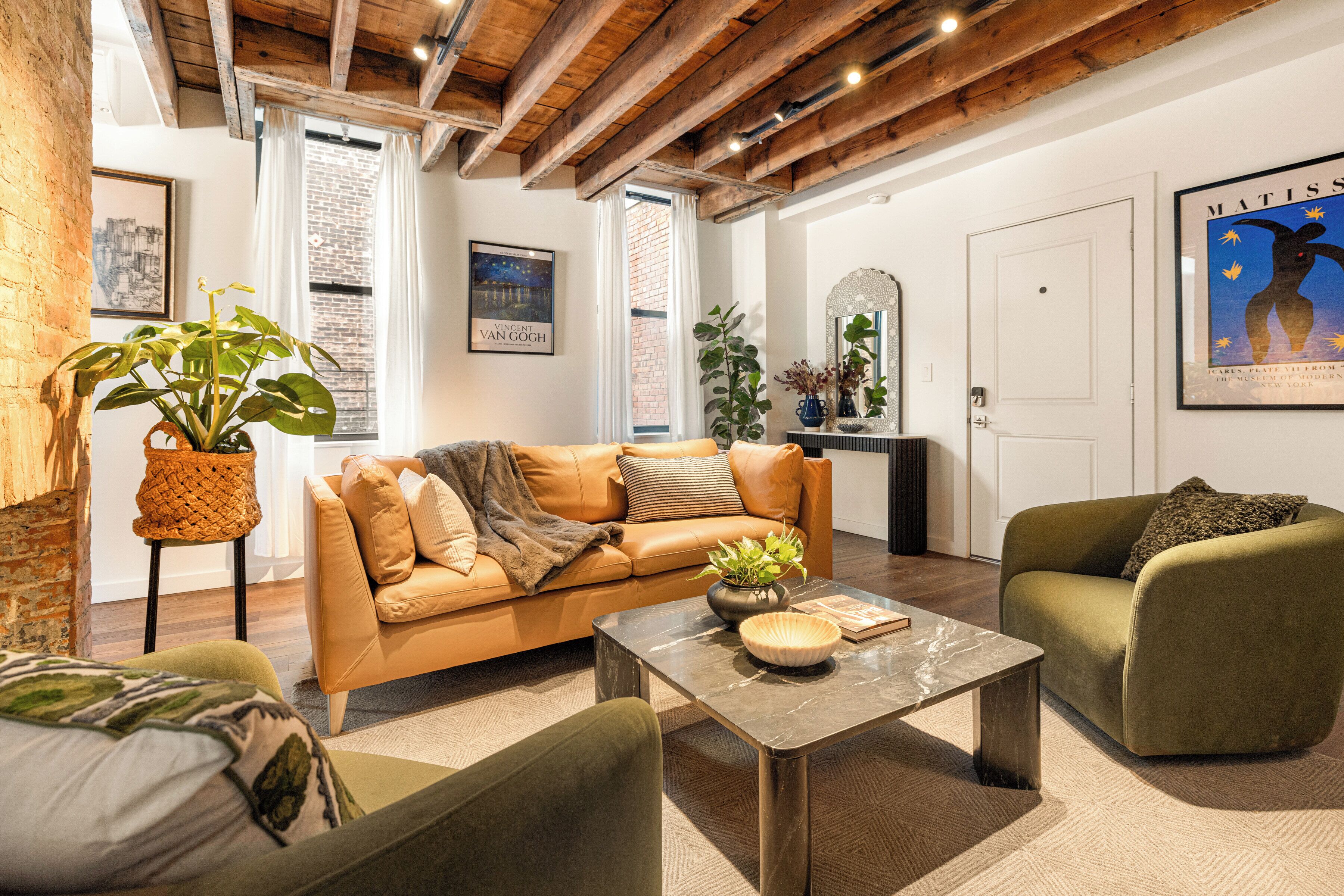 A furnished living room with a leather sofa, a coffee table, and a green armchair.