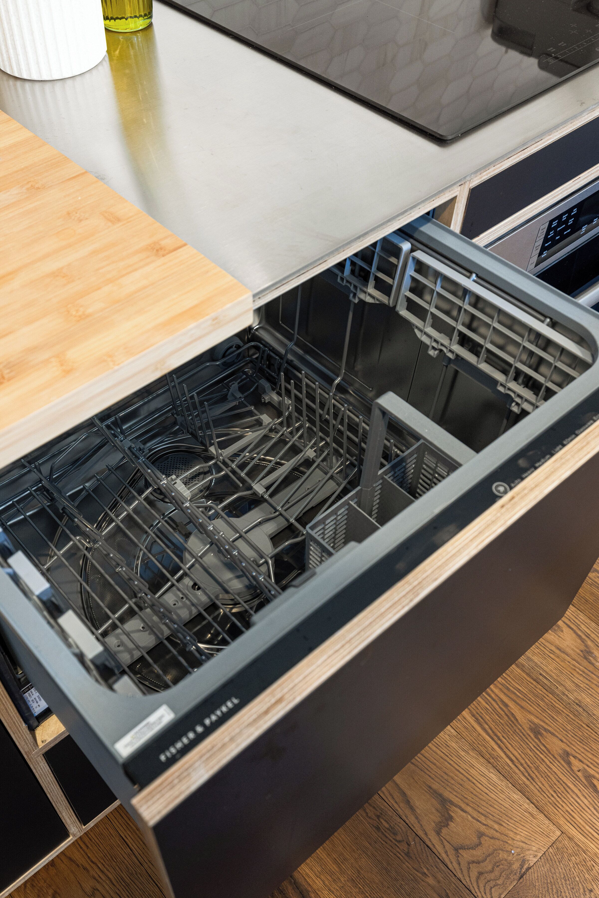 A kitchen with a dishwasher, wooden countertop, and a stainless steel backsplash.