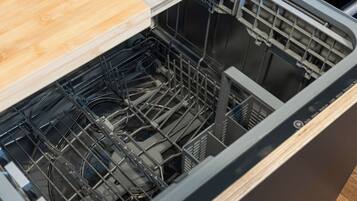 A kitchen with a dishwasher, wooden countertop, and a stainless steel backsplash.