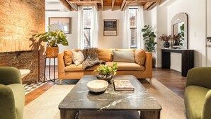 A living room with a sofa, coffee table, and a brick wall.