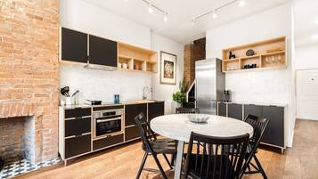 A modern kitchen with a brick wall, built-in appliances, and a dining area with a round table and chairs.