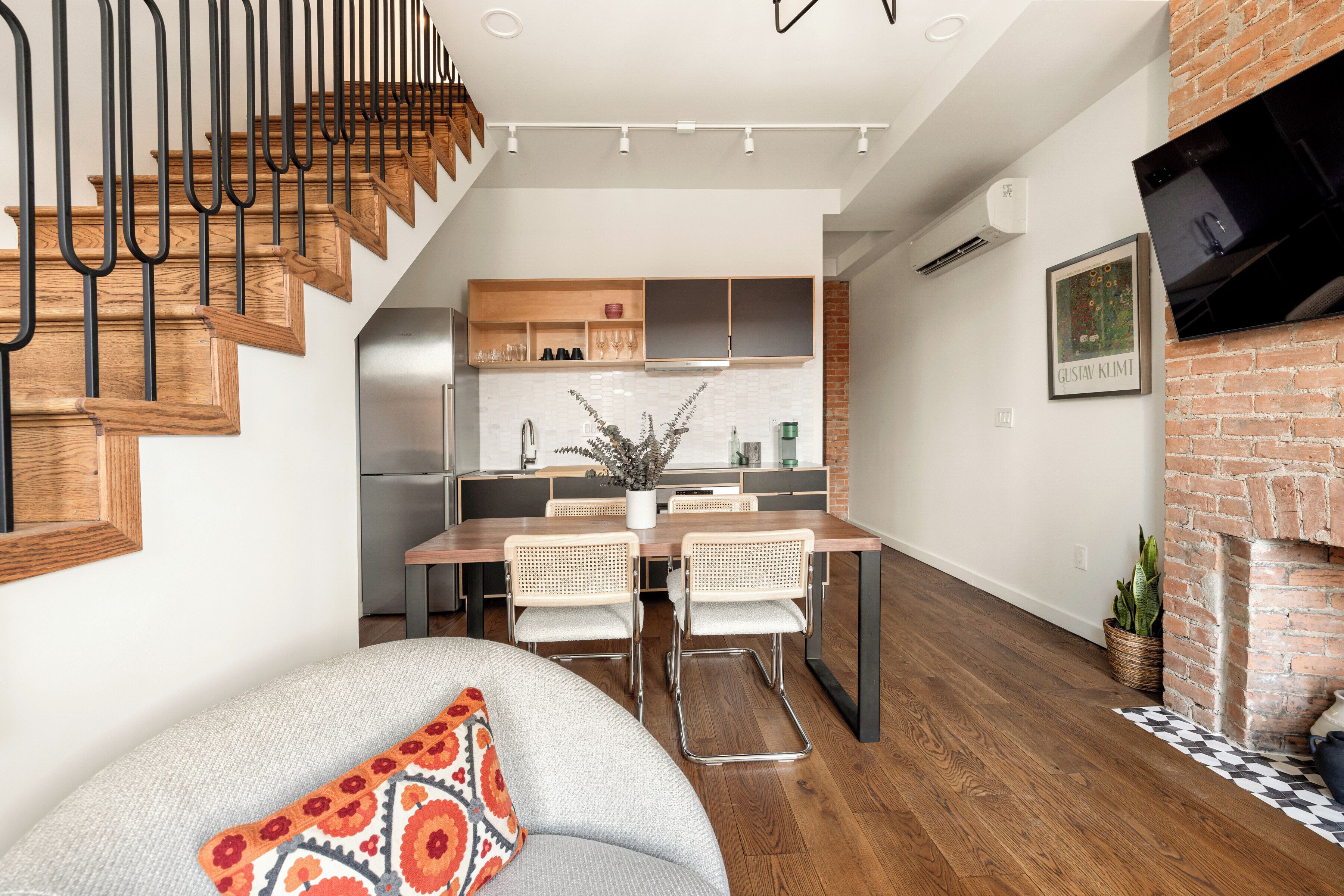 Una cocina moderna con armarios de madera, un comedor con dos sillas y una escalera con escalones de madera.