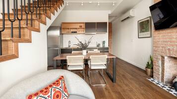 Una cocina moderna con armarios de madera, un comedor con dos sillas y una escalera con escalones de madera.