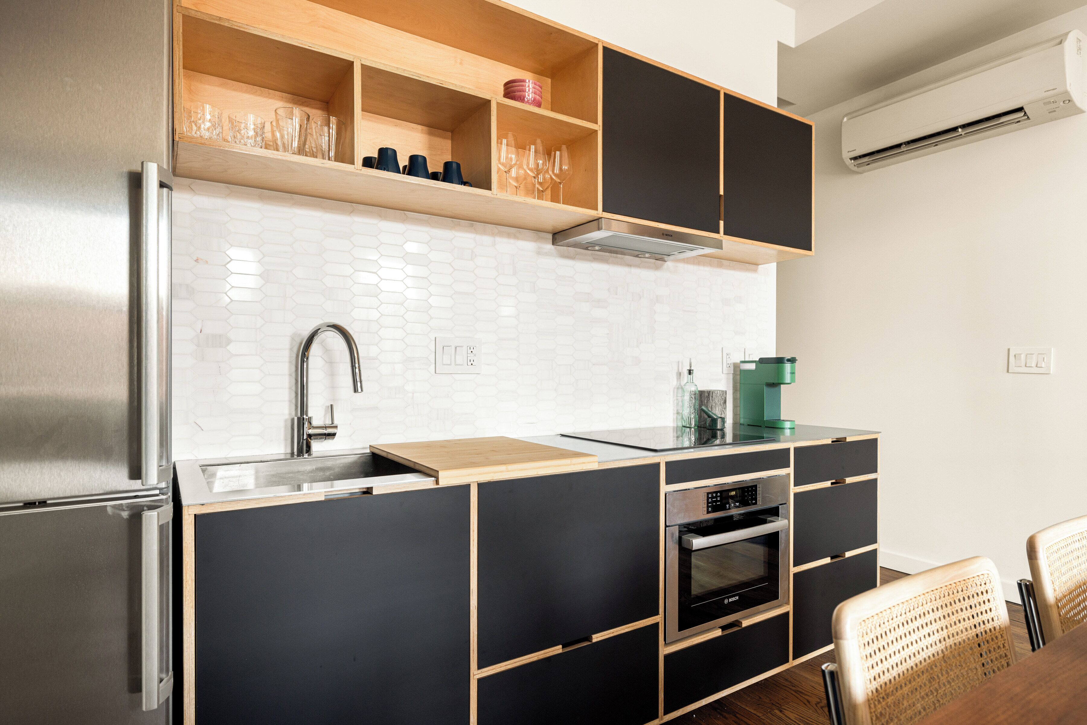 Una cocina moderna con horno empotrado, un lavabo y una cafetera.